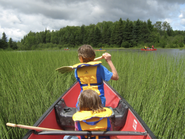 children paddle a canoe