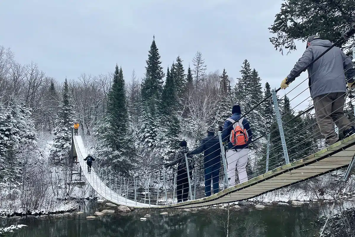 People walk over the Pinawa Suspension Bridge in Manitoba.