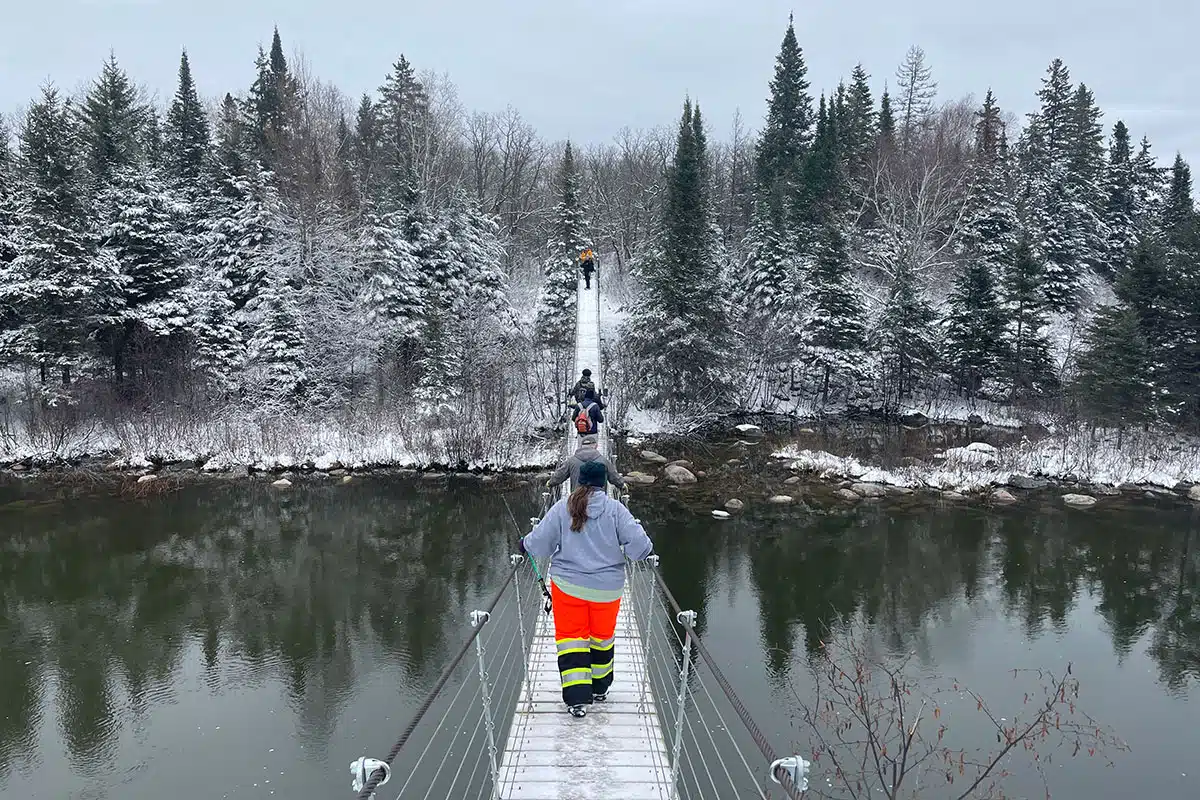 People walk over the Pinawa Suspension Bridge in Manitoba.