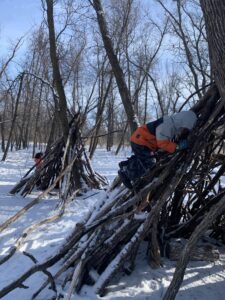 kids climbing on stick shelters in Bois des Esprits 2021 winter credit Mira Oberman